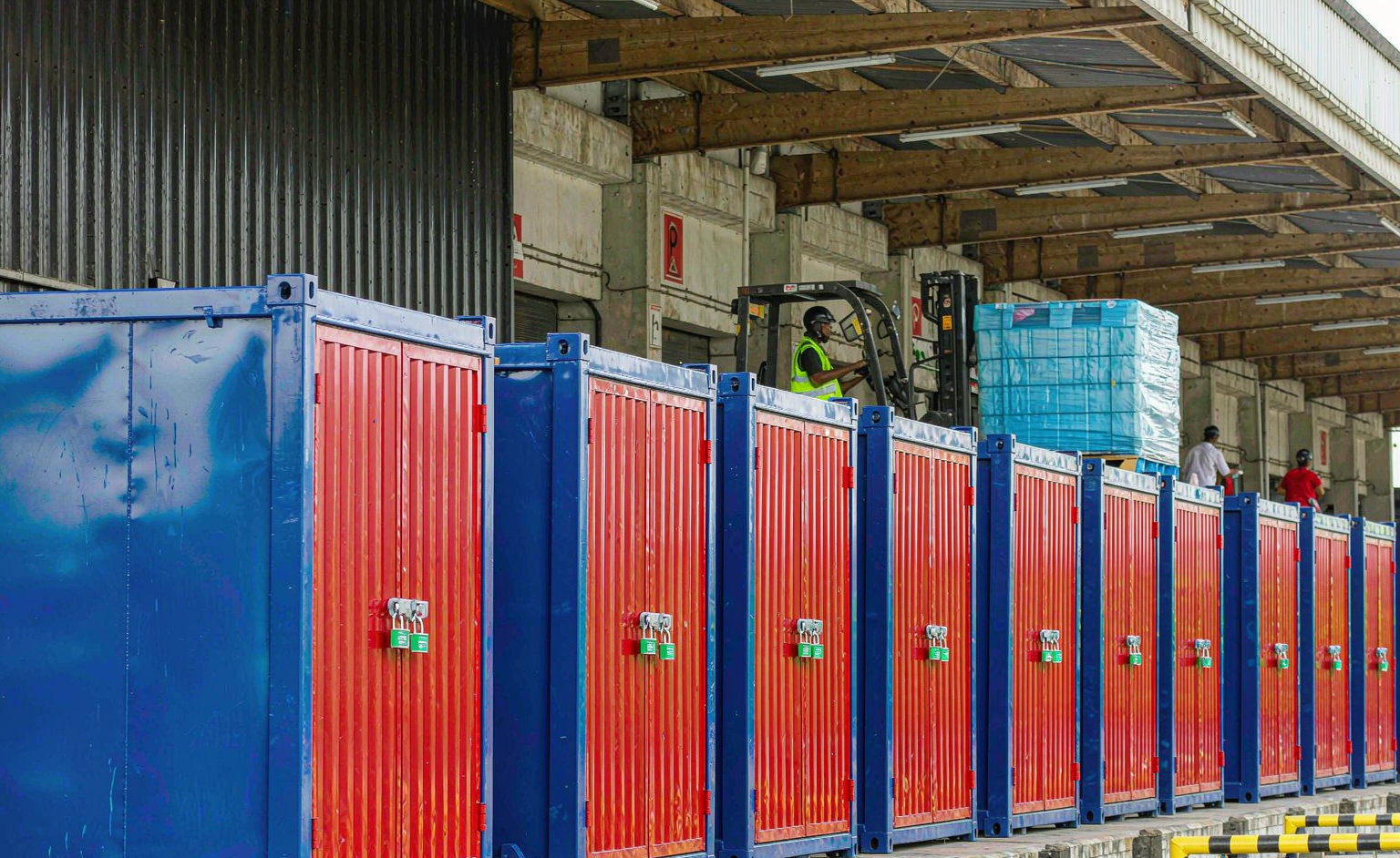 Workers loading cargo into shipping container with forklift